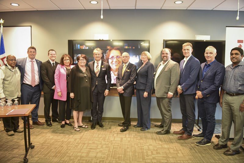 Several people pose for a formal photo at a funding announcement.